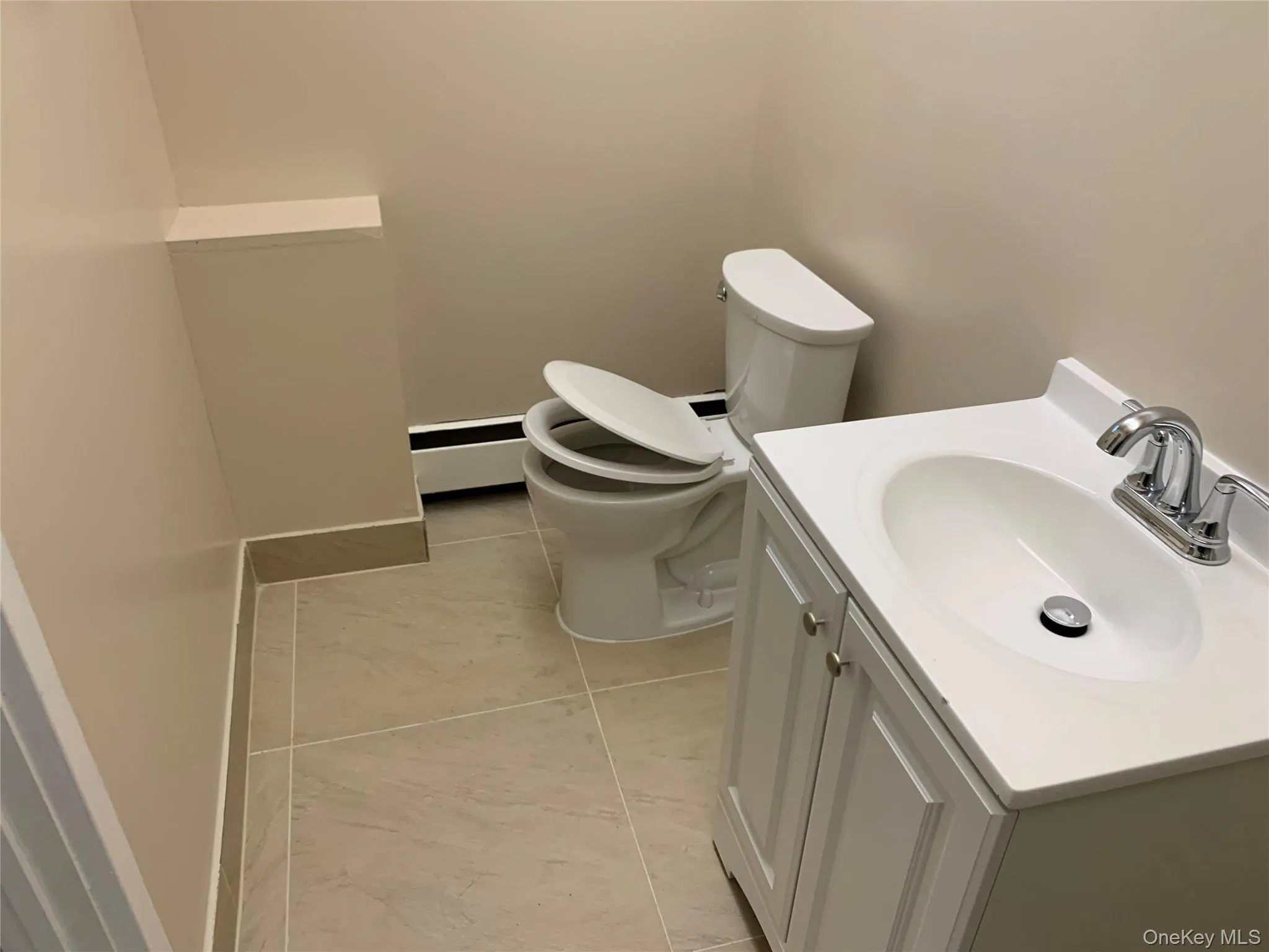 Bathroom with light tile patterned flooring, vanity, and baseboard heating Bathroom with light tile patterned flooring, vanity, and baseboard heating