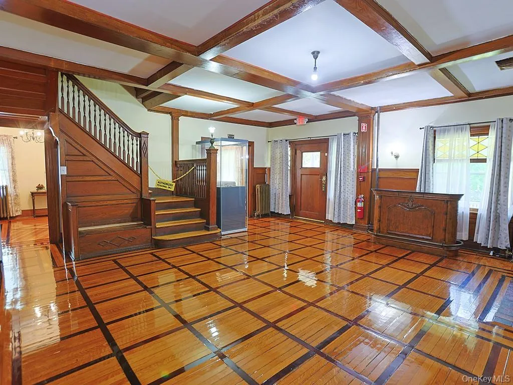 Unfurnished living room with coffered ceiling, healthy amount of natural light, beam ceiling, stairs, and radiator Unfurnished living room with coffered ceiling, healthy amount of natural light, beam ceiling, stairs, and radiator