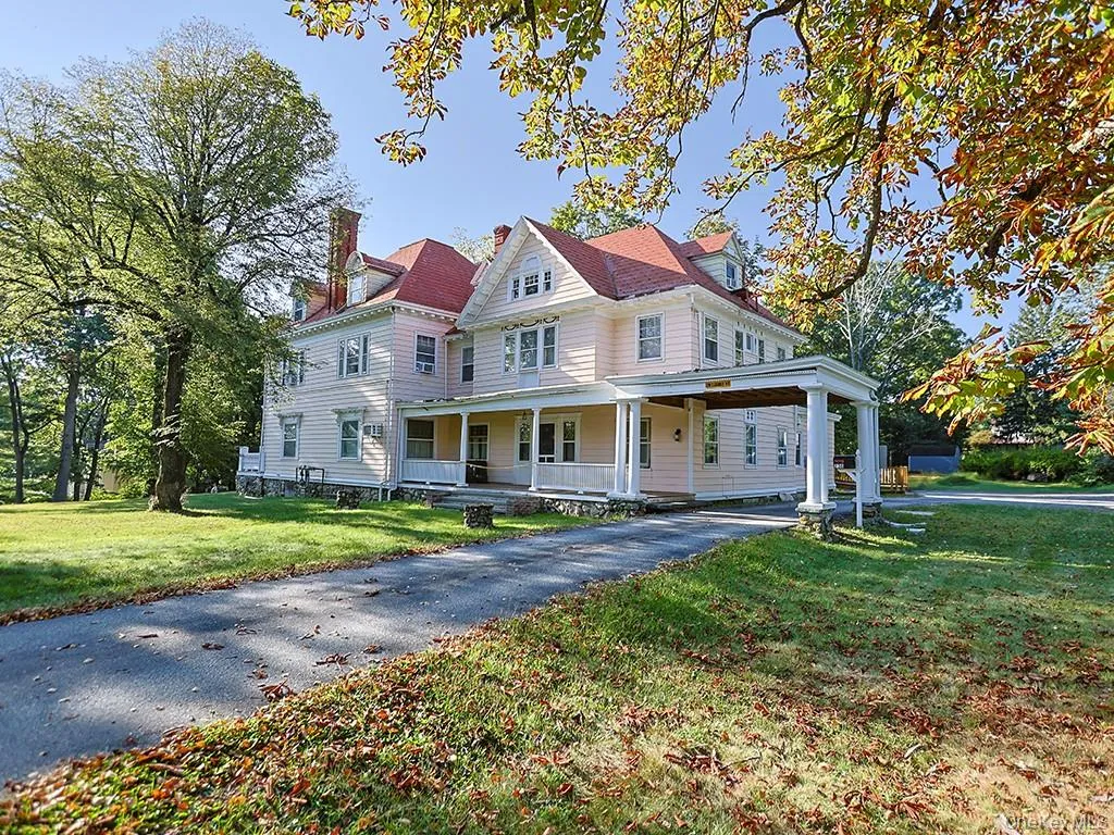 Victorian-style house featuring a chimney, a porch, a front yard, and asphalt driveway Victorian-style house featuring a chimney, a porch, a front yard, and asphalt driveway