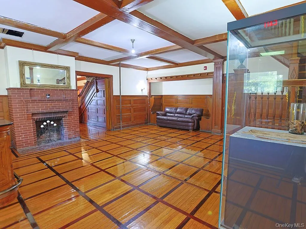 Living room with coffered ceiling, wainscoting, a decorative wall, inlaid floor details, and beamed ceiling Living room with coffered ceiling, wainscoting, a decorative wall, inlaid floor details, and beamed ceiling