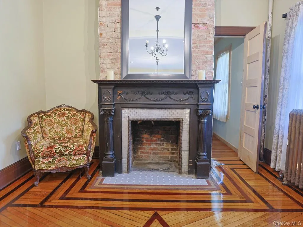 Detailed view of wood finished floors, a chandelier, and a large fireplace Detailed view of wood finished floors, a chandelier, and a large fireplace