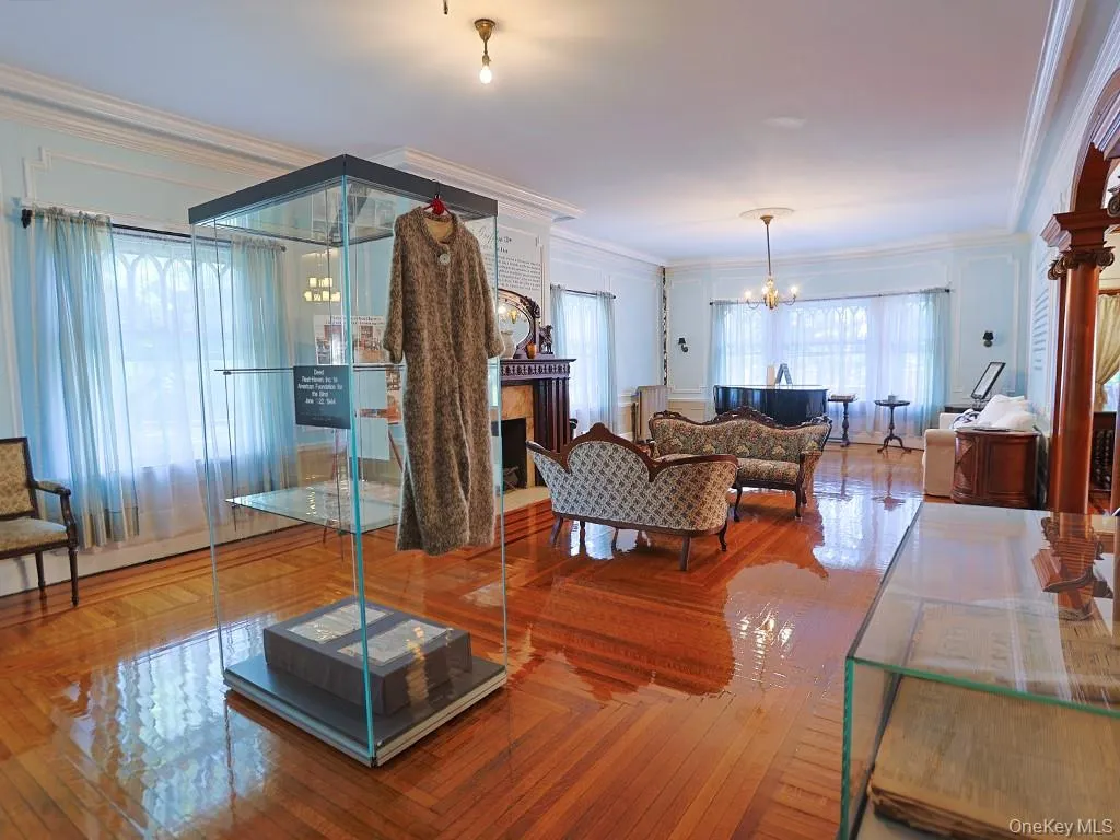Living area with a chandelier, ornamental molding, a fireplace, healthy amount of natural light, and parquet flooring Living area with a chandelier, ornamental molding, a fireplace, healthy amount of natural light, and parquet flooring