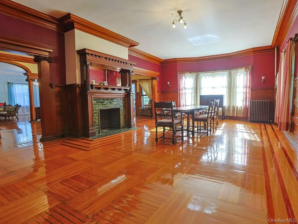 Dining room with ornamental molding, radiator, a fireplace, a wainscoted wall, and a decorative wall Dining room with ornamental molding, radiator, a fireplace, a wainscoted wall, and a decorative wall