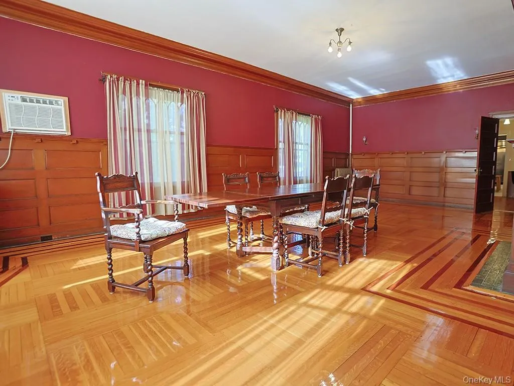 Dining space with wainscoting, ornamental molding, a wall mounted air conditioner, and a decorative wall Dining space with wainscoting, ornamental molding, a wall mounted air conditioner, and a decorative wall