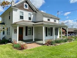 View of front of home featuring a porch, a front yard, and a chimney View of front of home featuring a porch, a front yard, and a chimney