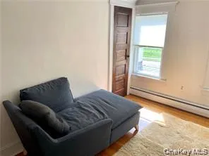 Living area with wood finished floors and a baseboard heating unit Living area with wood finished floors and a baseboard heating unit