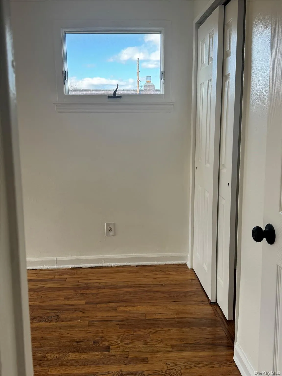 Unfurnished bedroom with dark wood-style flooring, multiple windows, and a closet Unfurnished bedroom with dark wood-style flooring, multiple windows, and a closet