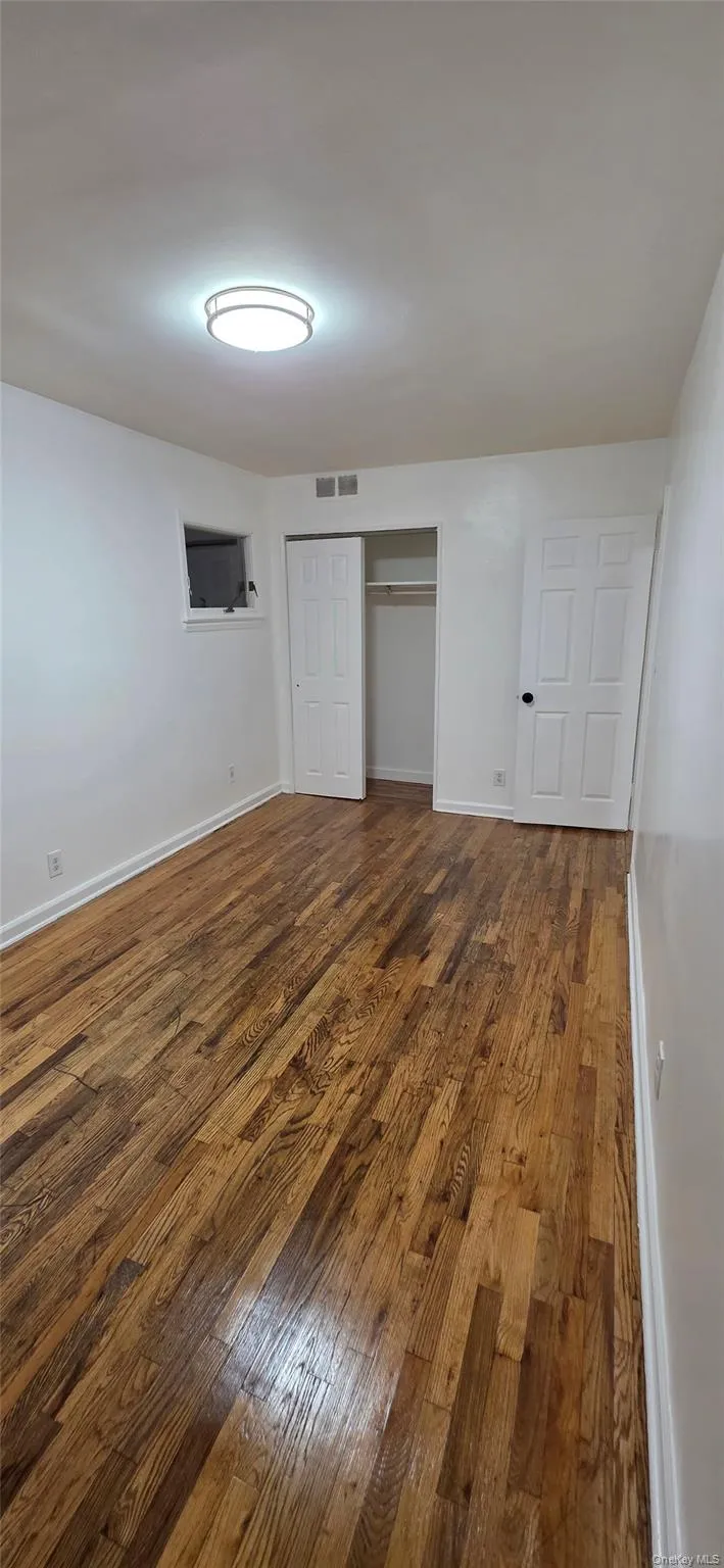 Unfurnished bedroom with dark wood-style flooring and a closet Unfurnished bedroom with dark wood-style flooring and a closet