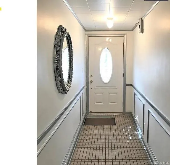 Entryway featuring a decorative wall, tile patterned flooring, and wainscoting Entryway featuring a decorative wall, tile patterned flooring, and wainscoting