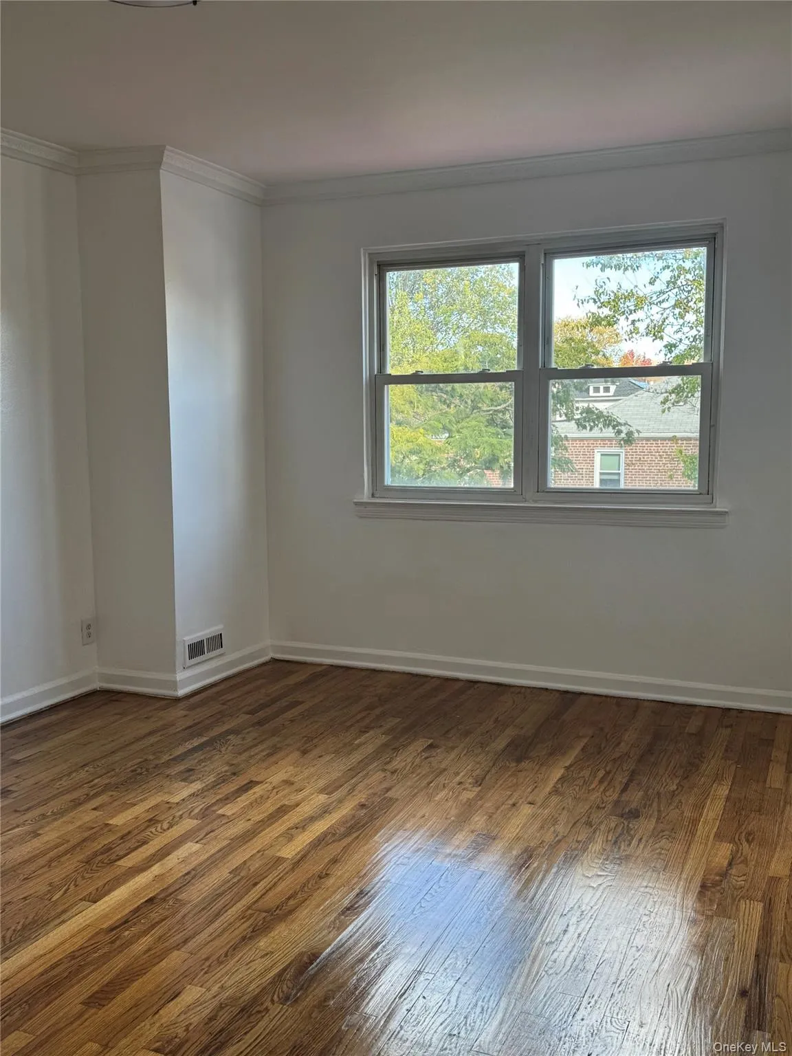 Spare room featuring crown molding, healthy amount of natural light, and dark wood-type flooring Spare room featuring crown molding, healthy amount of natural light, and dark wood-type flooring