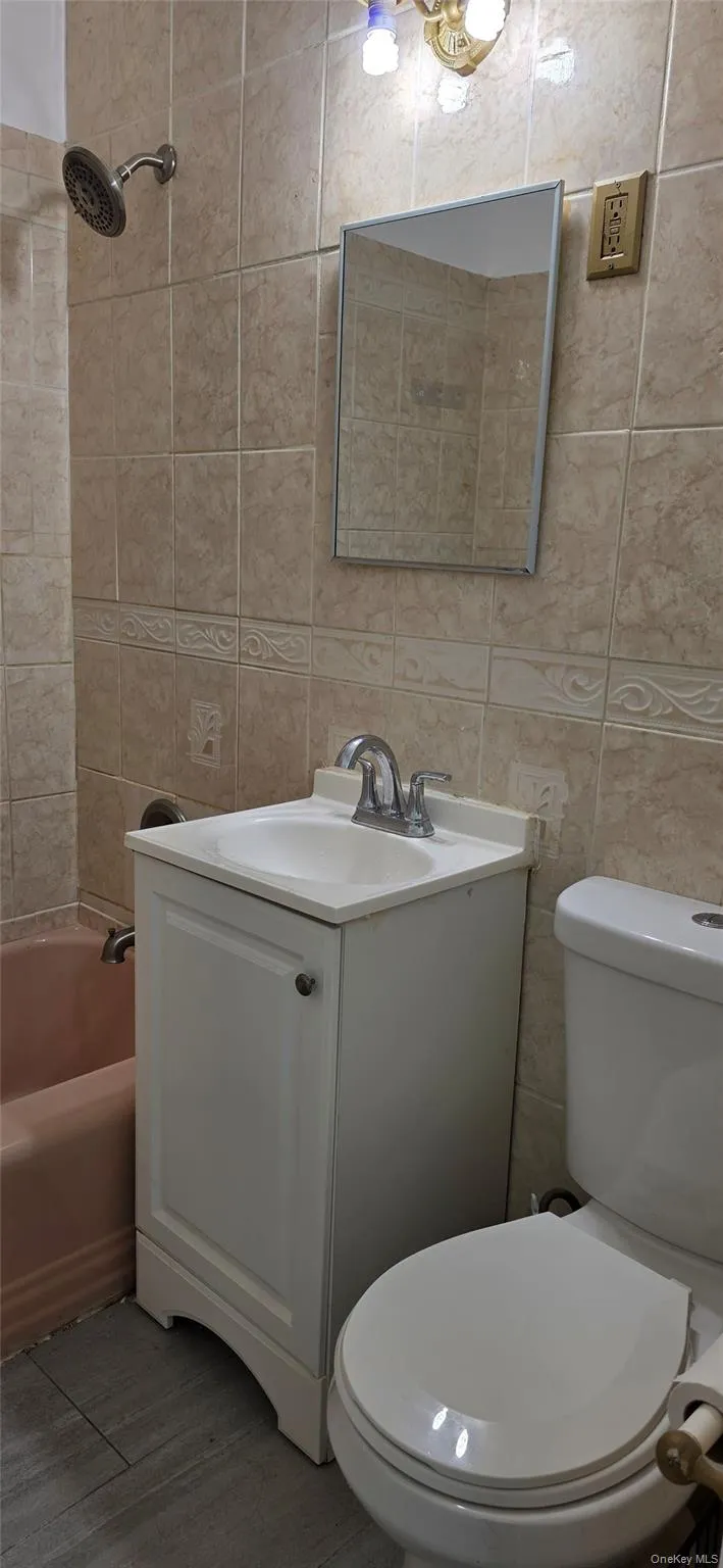 Bathroom with tile walls, vanity, and bathtub / shower combination Bathroom with tile walls, vanity, and bathtub / shower combination