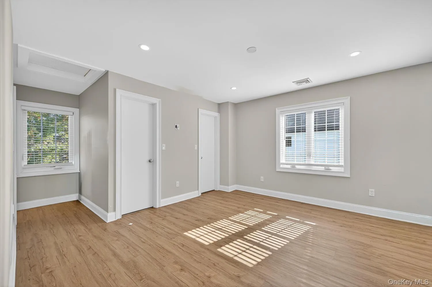 Unfurnished bedroom with attic access, light wood-type flooring, multiple windows, and recessed lighting Unfurnished bedroom with attic access, light wood-type flooring, multiple windows, and recessed lighting
