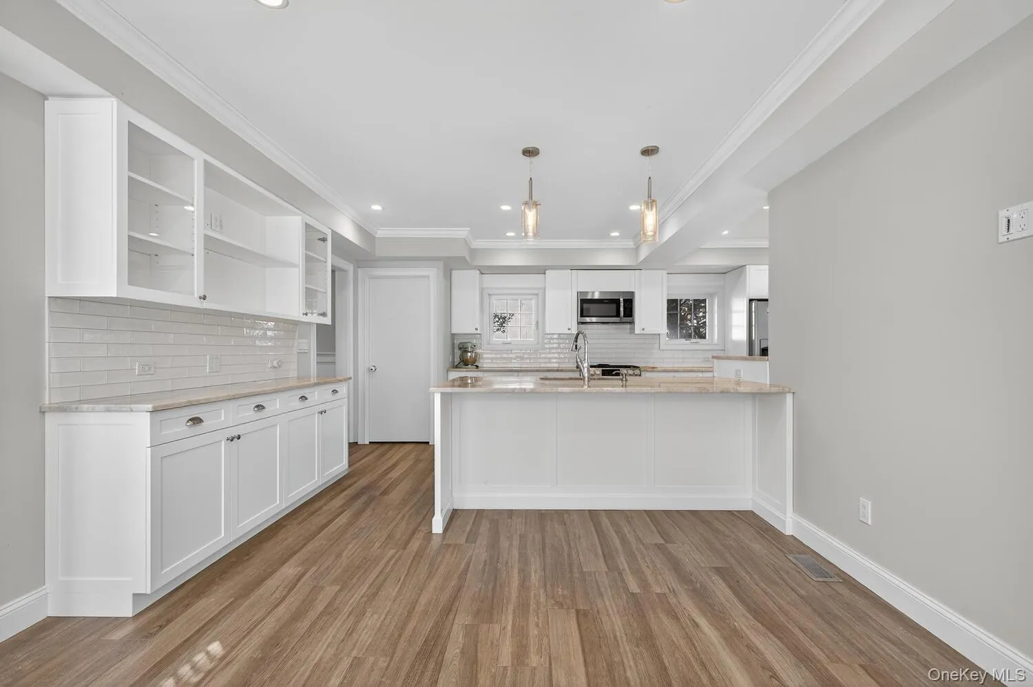 Kitchen with white cabinets, open shelves, light stone counters, light wood finished floors, and hanging light fixtures Kitchen with white cabinets, open shelves, light stone counters, light wood finished floors, and hanging light fixtures