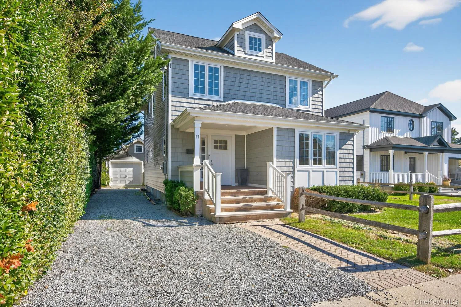Traditional style home with a porch, a garage, roof with shingles, and gravel driveway Traditional style home with a porch, a garage, roof with shingles, and gravel driveway