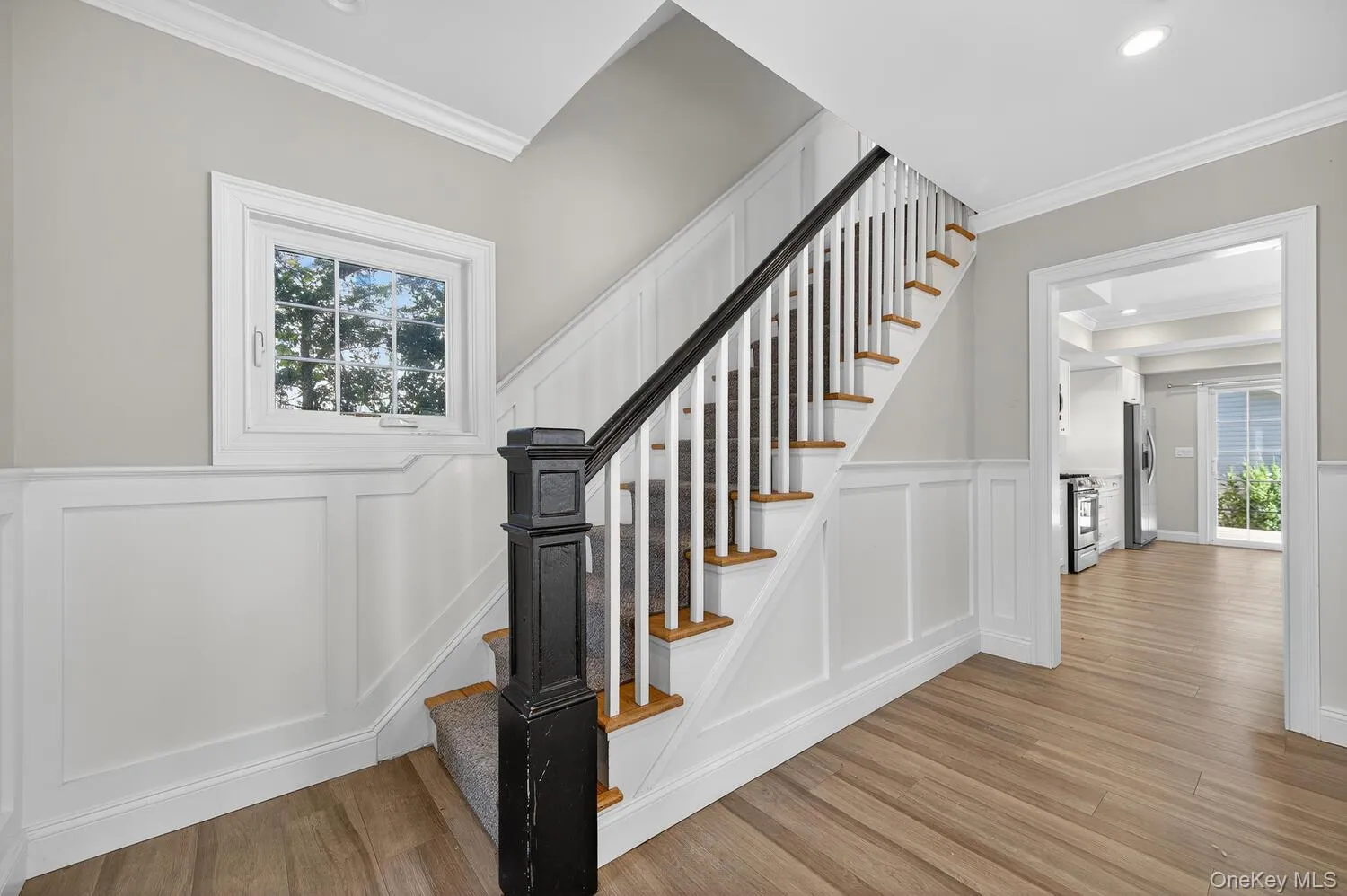 Stairs featuring healthy amount of natural light, ornamental molding, wood finished floors, a decorative wall, and wainscoting Stairs featuring healthy amount of natural light, ornamental molding, wood finished floors, a decorative wall, and wainscoting