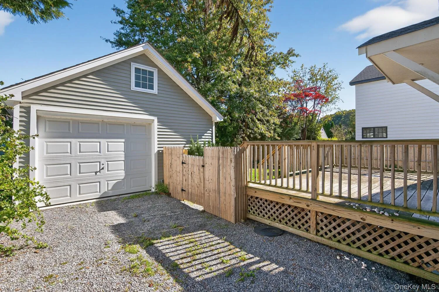 View of side of home with a deck, a garage, driveway, and an outdoor structure View of side of home with a deck, a garage, driveway, and an outdoor structure