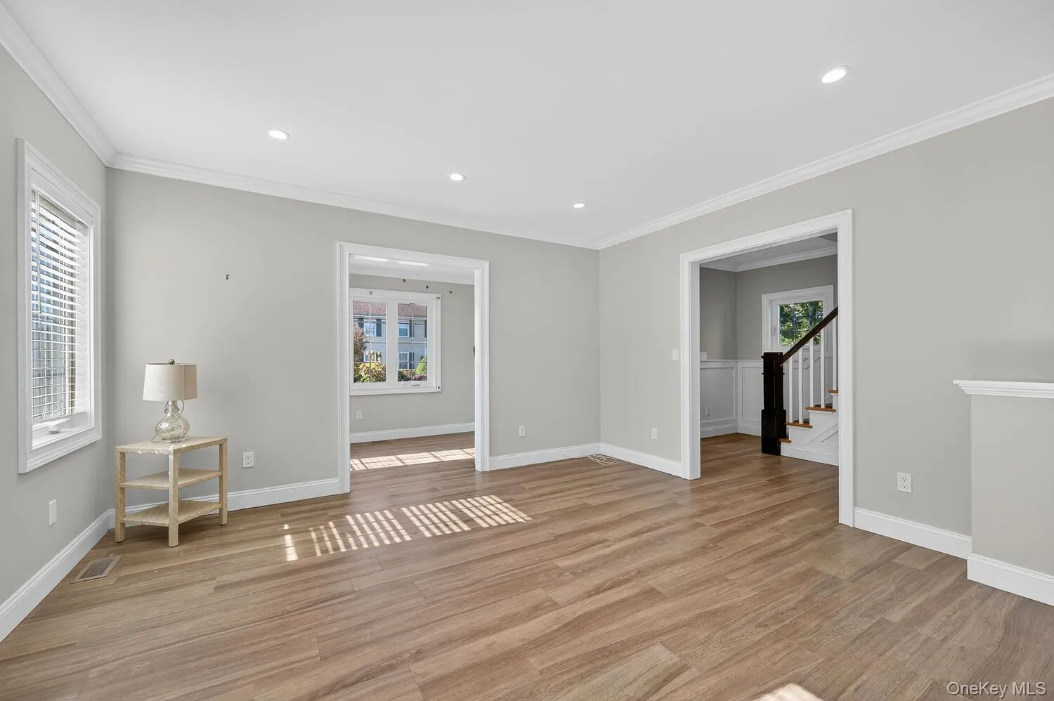 Unfurnished room with ornamental molding, light wood-type flooring, recessed lighting, and stairs Unfurnished room with ornamental molding, light wood-type flooring, recessed lighting, and stairs