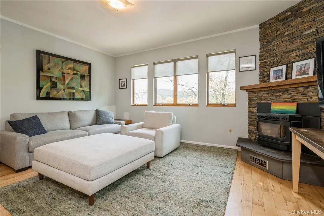 Large windows with views of the lake, trees and mountains. A stacked slate fireplace features a pellet stove. Large windows with views of the lake, trees and mountains. A stacked slate fireplace features a pellet stove.