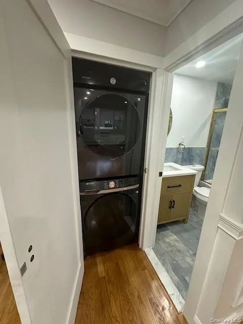 Laundry room featuring light wood-style floors and stacked washing machine and dryer Laundry room featuring light wood-style floors and stacked washing machine and dryer