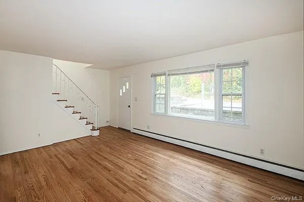 Foyer with a baseboard radiator, stairway, and light wood-style flooring Foyer with a baseboard radiator, stairway, and light wood-style flooring