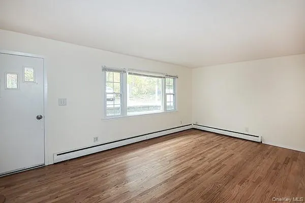 Empty room featuring a baseboard heating unit and wood finished floors Empty room featuring a baseboard heating unit and wood finished floors