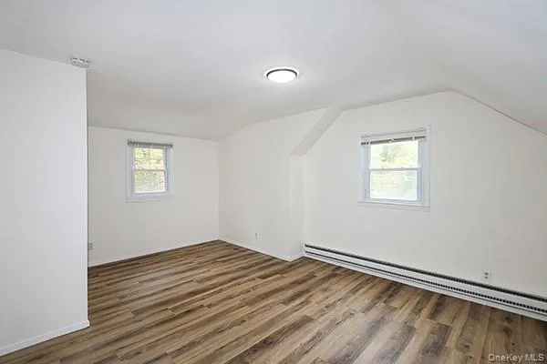 Bonus room with a baseboard radiator, wood finished floors, healthy amount of natural light, and lofted ceiling Bonus room with a baseboard radiator, wood finished floors, healthy amount of natural light, and lofted ceiling