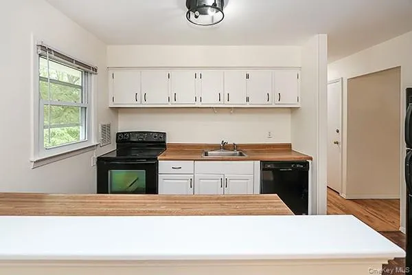 Kitchen with black appliances, white cabinets, and dark wood-type flooring Kitchen with black appliances, white cabinets, and dark wood-type flooring