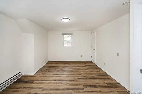 Spare room with baseboard heating and dark wood-style flooring Spare room with baseboard heating and dark wood-style flooring