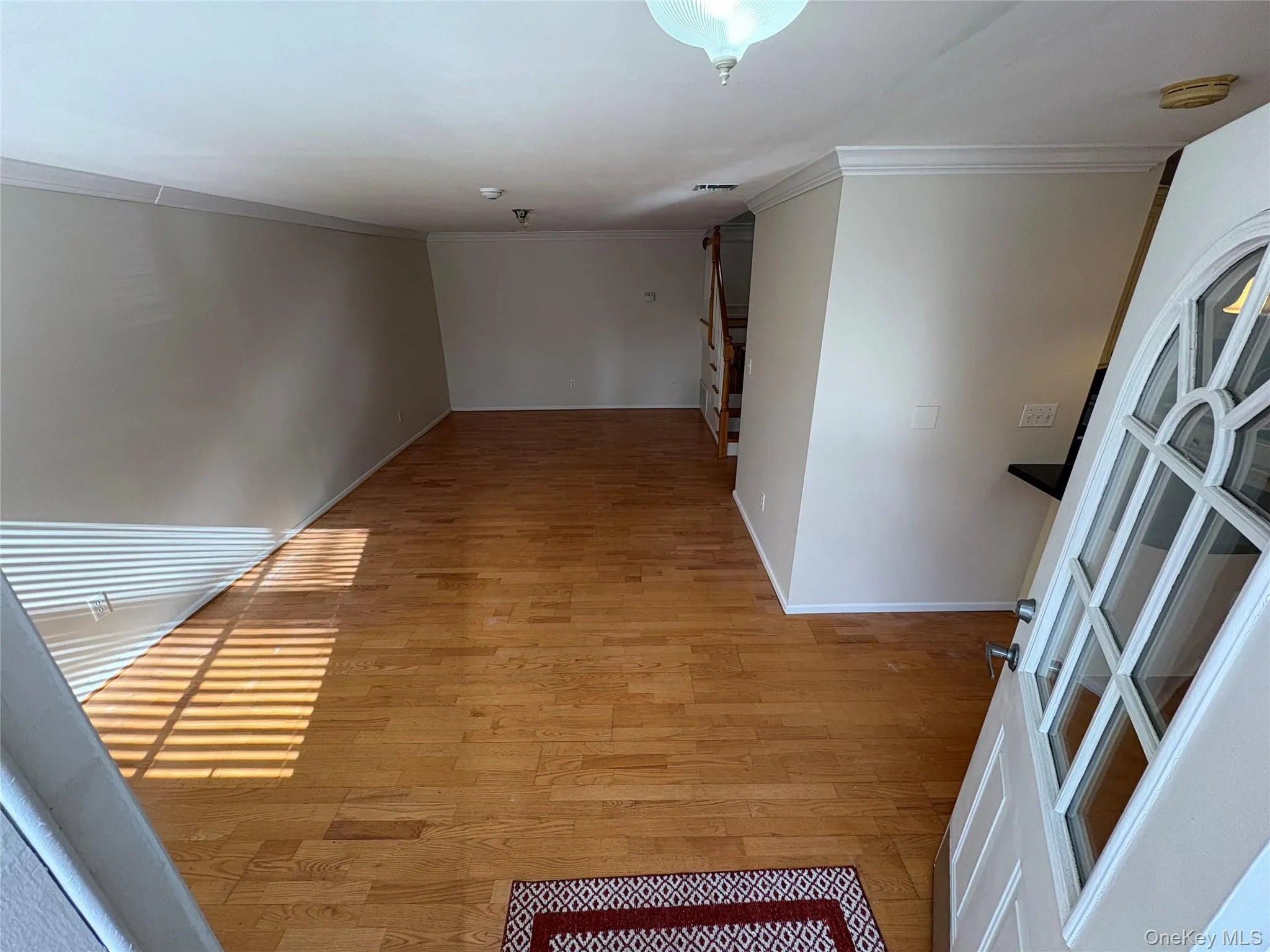 Hallway featuring light wood-style floors, crown molding, and stairway Hallway featuring light wood-style floors, crown molding, and stairway