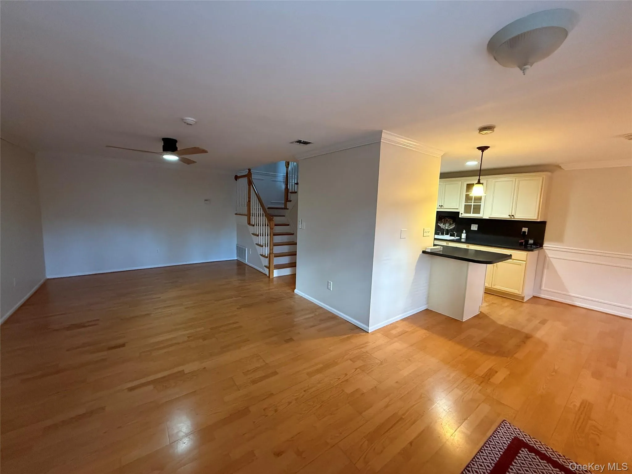 Unfurnished living room with stairs, light wood-style floors, crown molding, and ceiling fan Unfurnished living room with stairs, light wood-style floors, crown molding, and ceiling fan