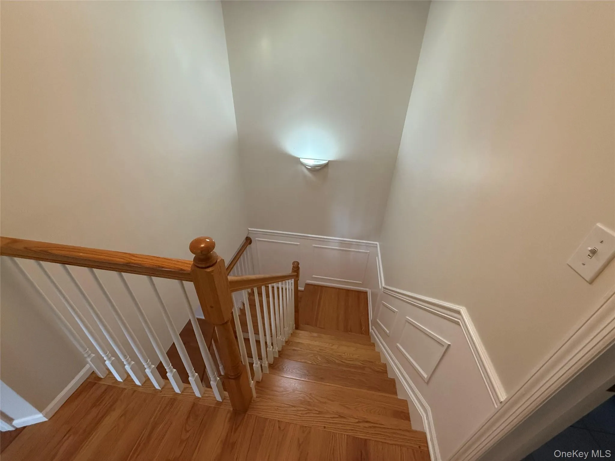Stairway with wood finished floors, a decorative wall, and a wainscoted wall Stairway with wood finished floors, a decorative wall, and a wainscoted wall