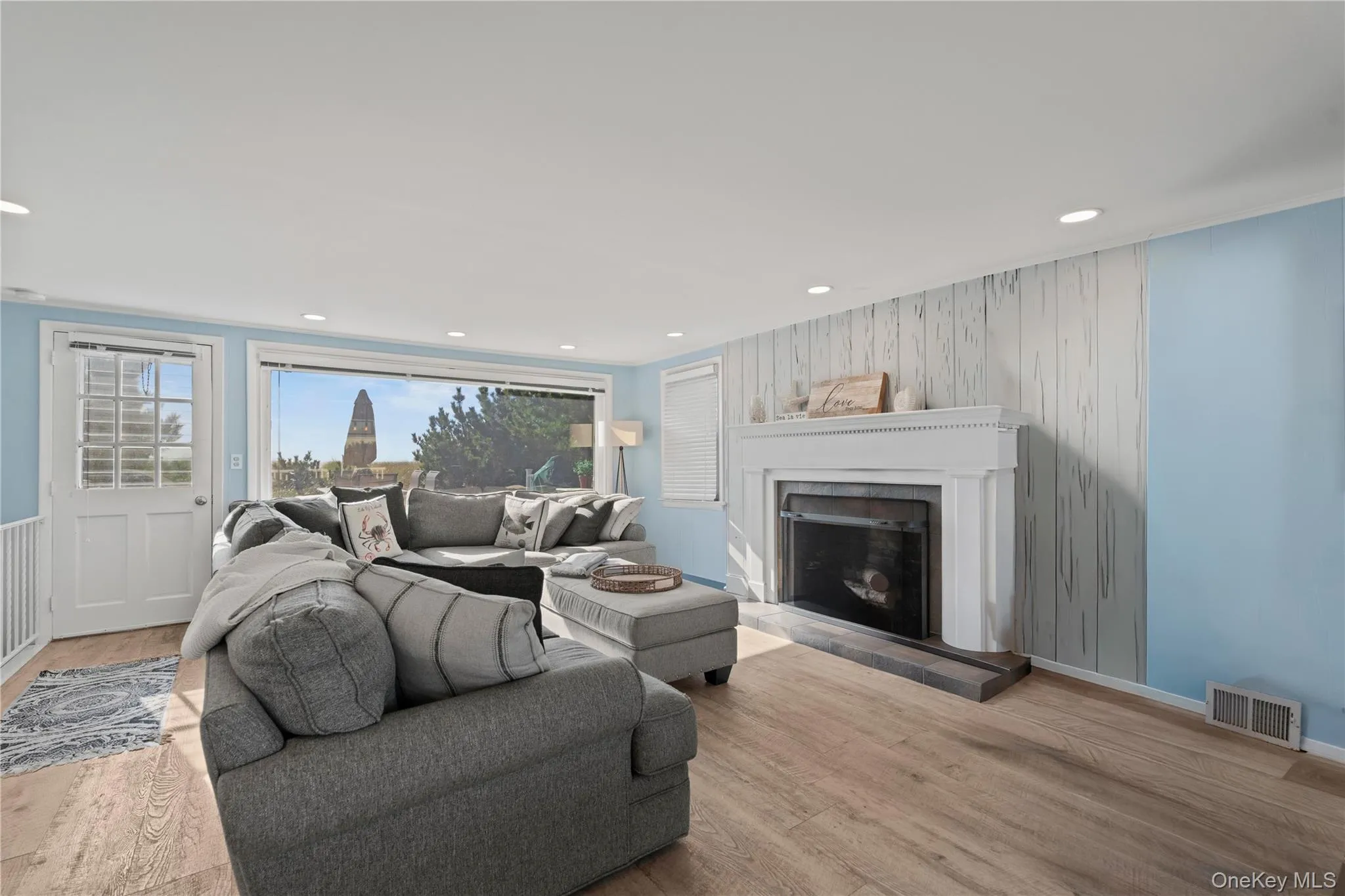 Open Living room with wood finished floors, a fireplace with raised hearth, wooden walls, and recessed lighting Open Living room with wood finished floors, a fireplace with raised hearth, wooden walls, and recessed lighting