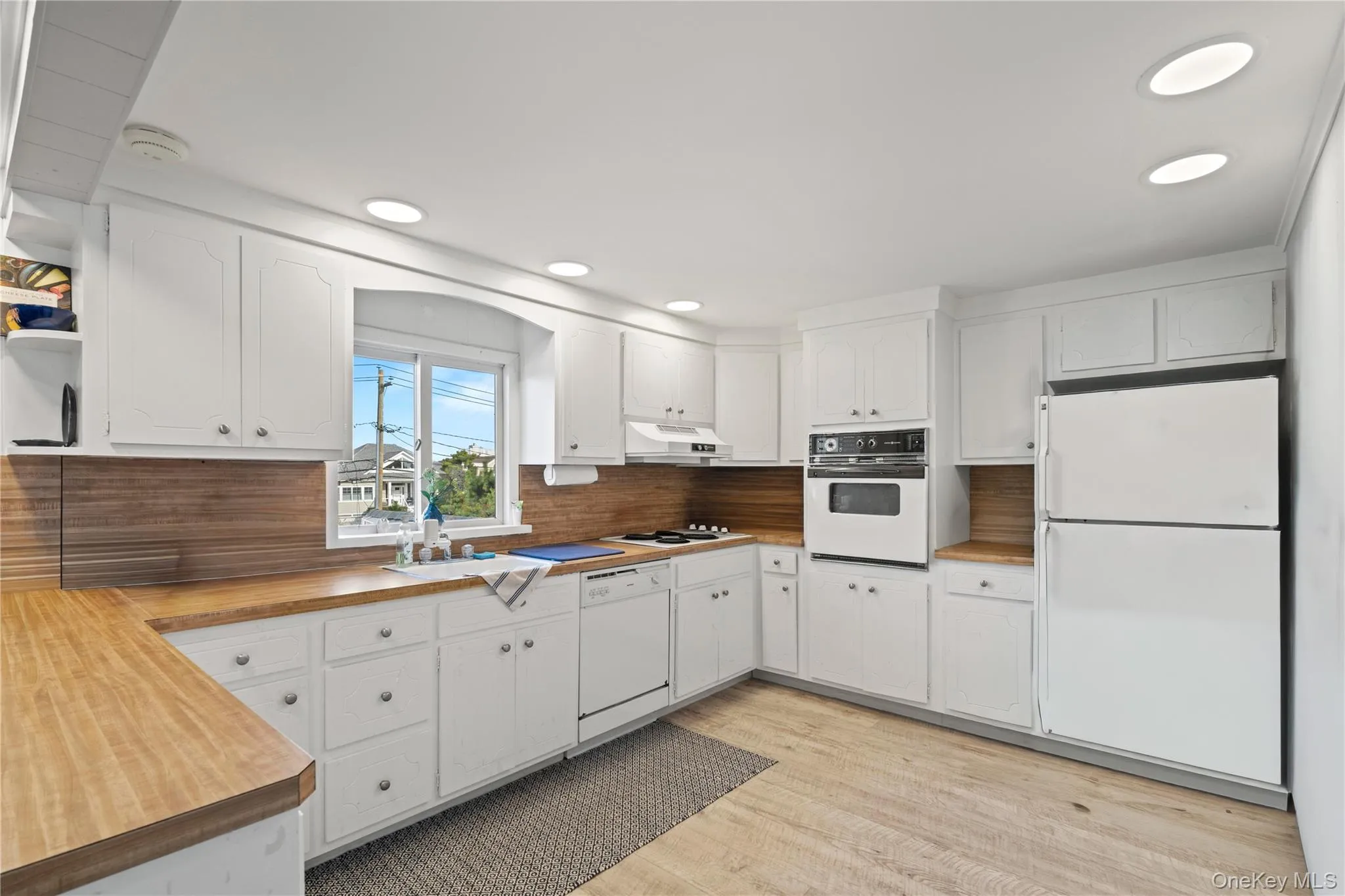 Open Kitchen featuring white appliances, white cabinets, light wood-type flooring, recessed lighting, and open shelves Open Kitchen featuring white appliances, white cabinets, light wood-type flooring, recessed lighting, and open shelves