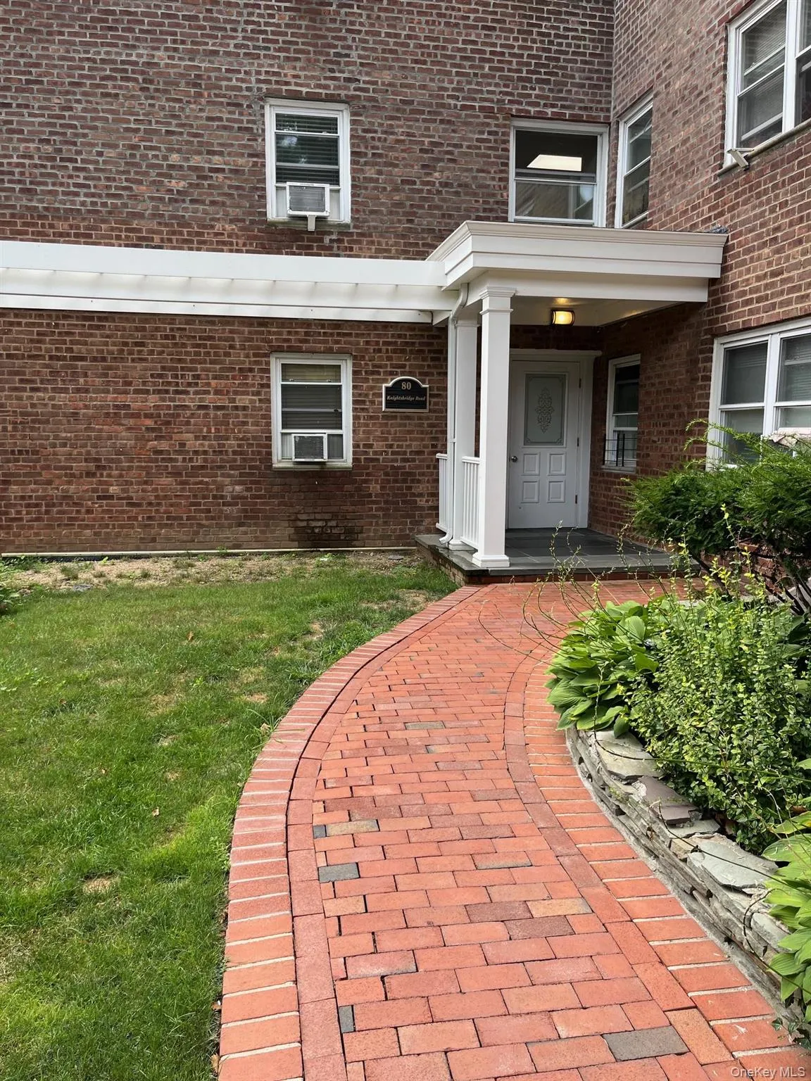 Entrance to property featuring brick siding and a lawn Entrance to property featuring brick siding and a lawn