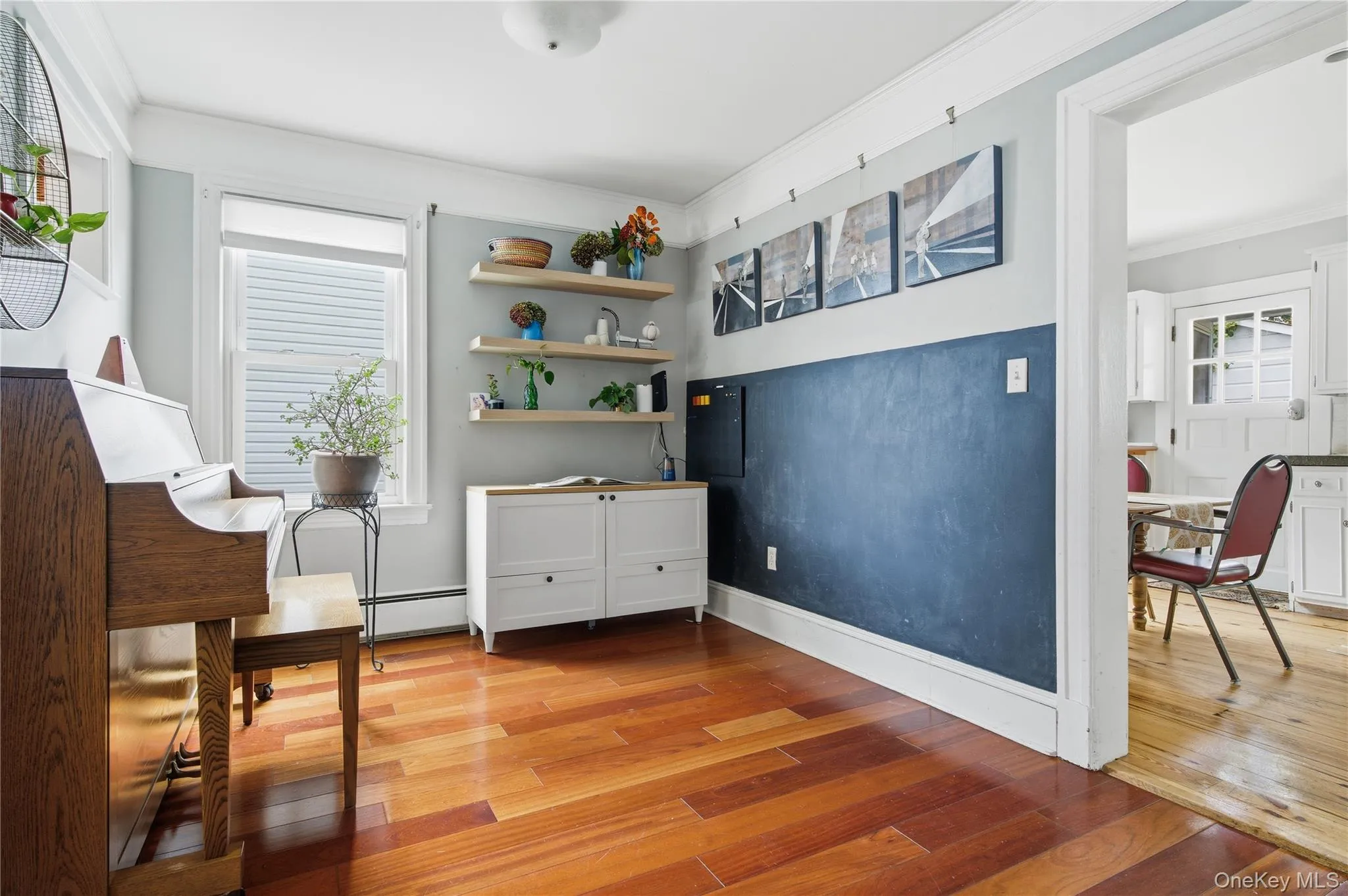 Living area featuring crown molding, light wood-style flooring, and a baseboard radiator Living area featuring crown molding, light wood-style flooring, and a baseboard radiator