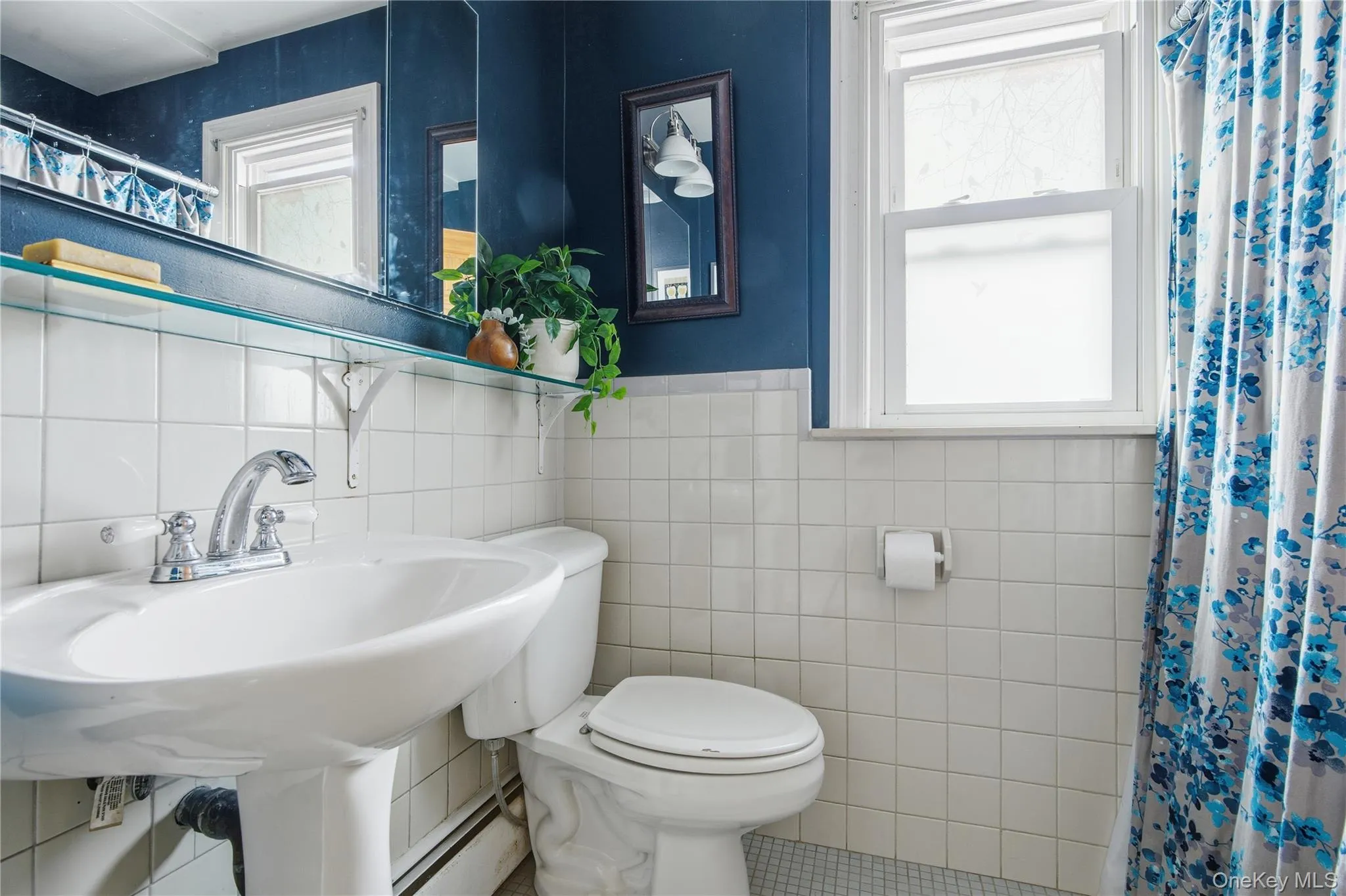 Full bathroom with curtained shower, tile walls, a baseboard heating unit, healthy amount of natural light, and tile patterned flooring Full bathroom with curtained shower, tile walls, a baseboard heating unit, healthy amount of natural light, and tile patterned flooring