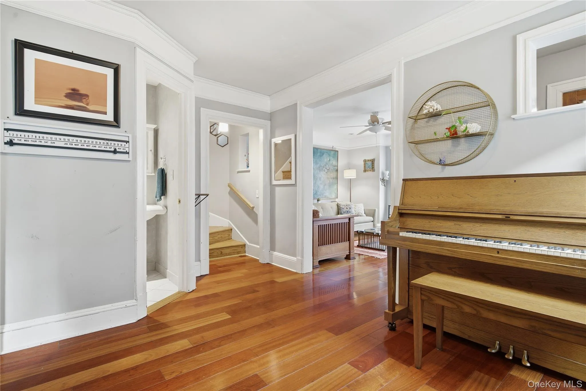 Hallway featuring crown molding, light wood-type flooring, and stairs Hallway featuring crown molding, light wood-type flooring, and stairs