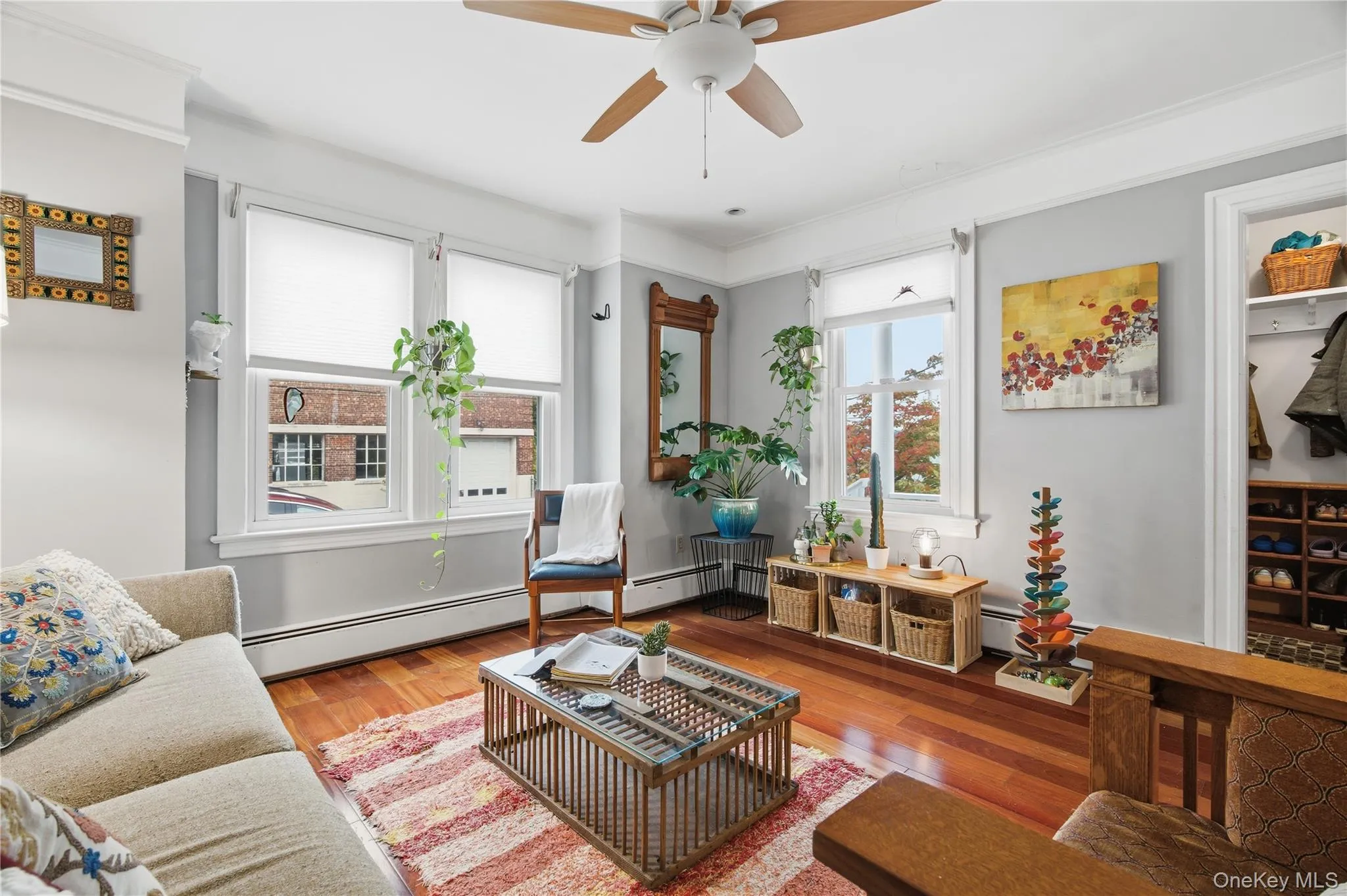 Living area featuring wood finished floors, ceiling fan, and baseboard heating Living area featuring wood finished floors, ceiling fan, and baseboard heating