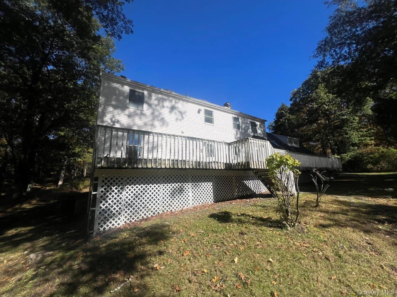 Rear view of house featuring a lawn and a wooden deck Rear view of house featuring a lawn and a wooden deck