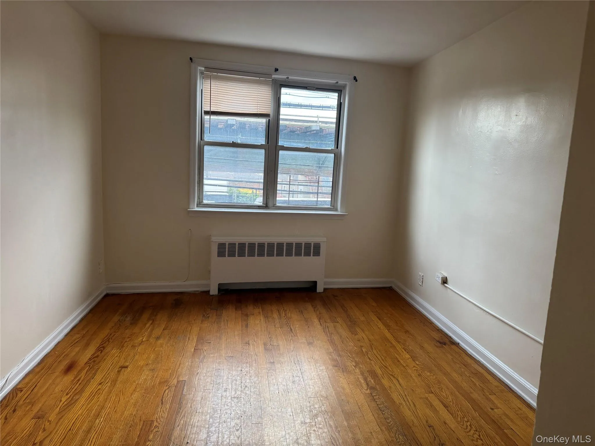 Empty room with radiator and light wood-style floors Empty room with radiator and light wood-style floors