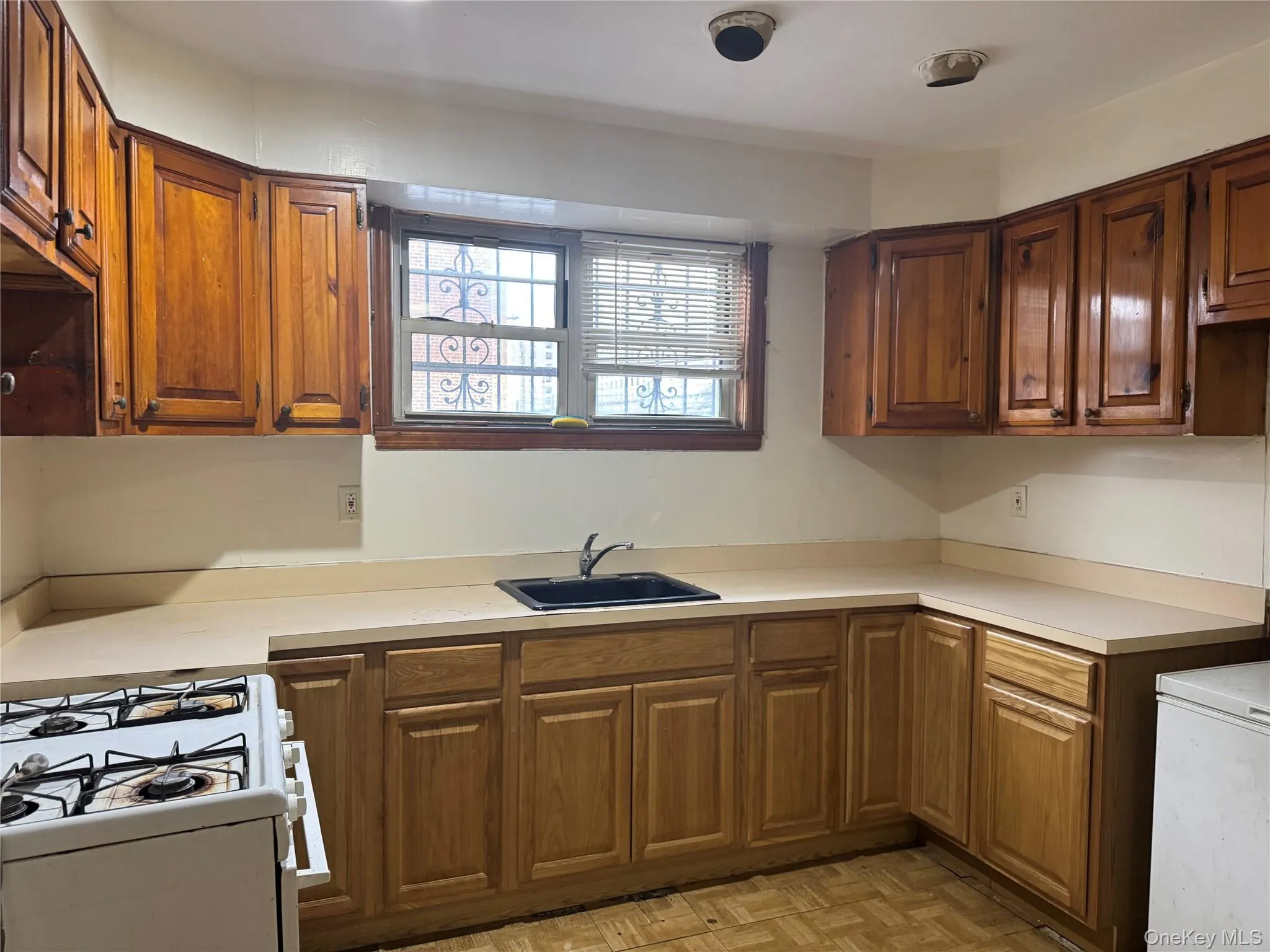 Kitchen featuring light countertops, brown cabinets, and white range with gas cooktop Kitchen featuring light countertops, brown cabinets, and white range with gas cooktop