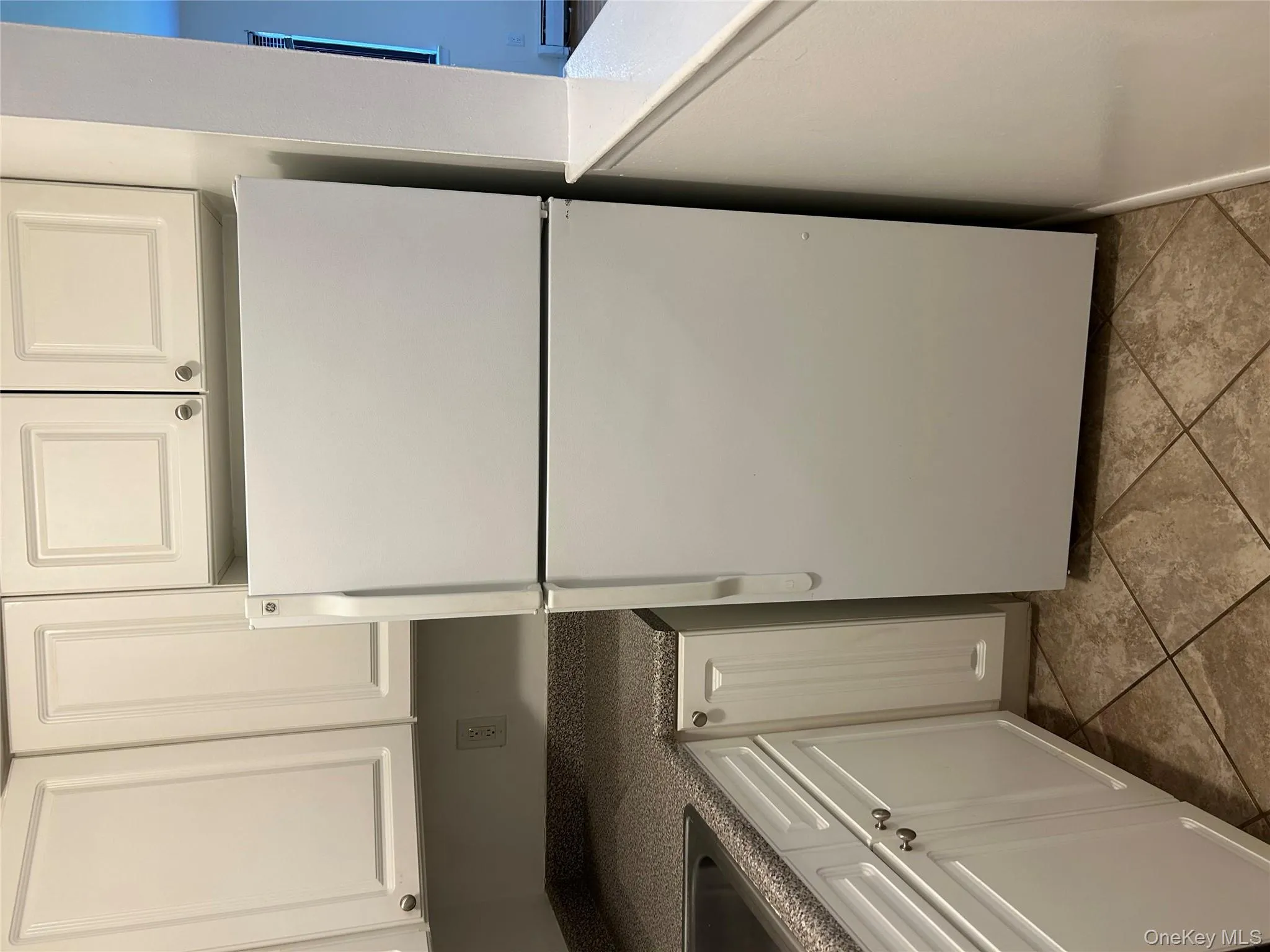 Kitchen featuring white cabinets, freestanding refrigerator, dark countertops, and a baseboard heating unit Kitchen featuring white cabinets, freestanding refrigerator, dark countertops, and a baseboard heating unit