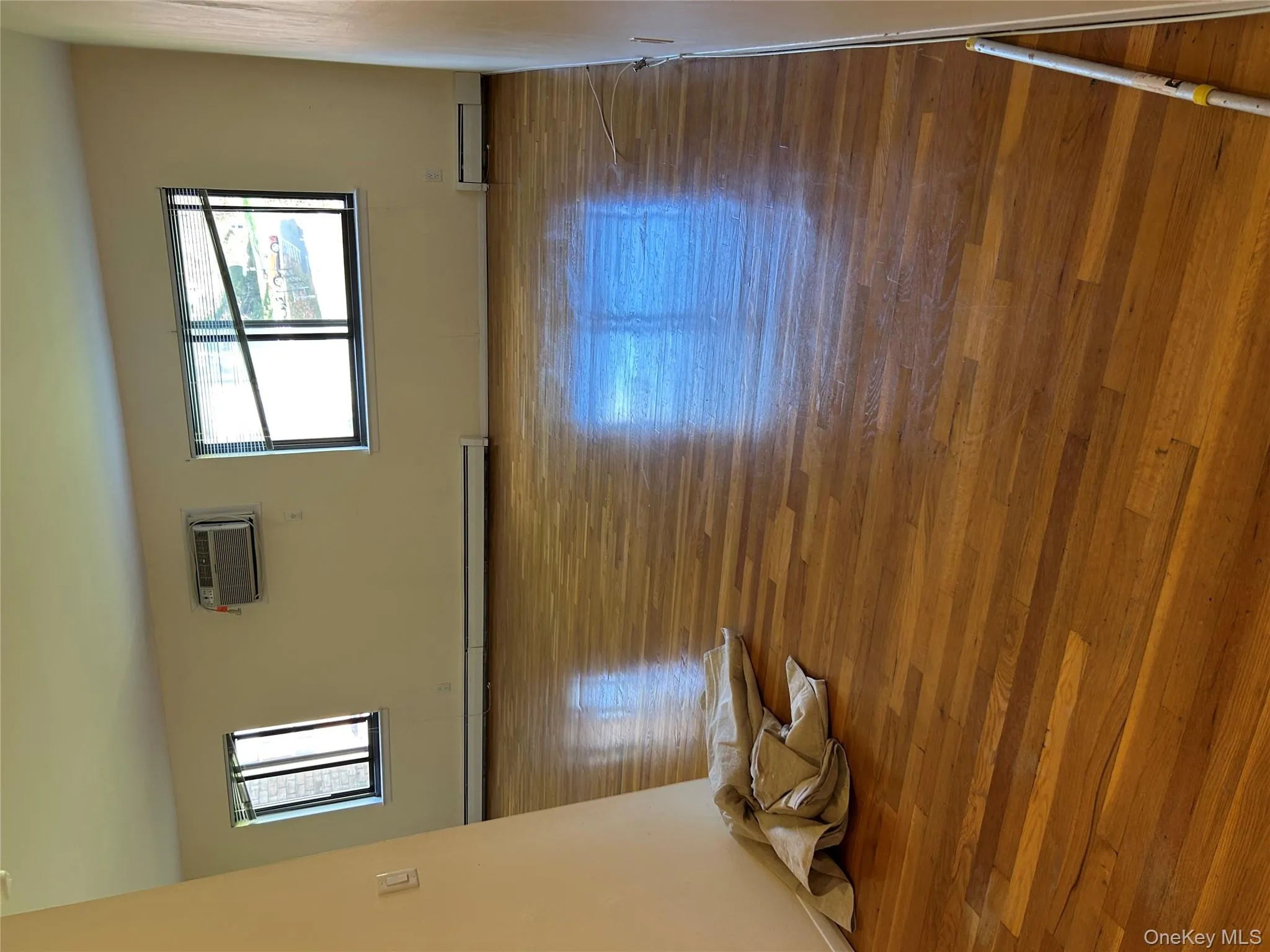 Empty room with hardwood / wood-style floors, baseboard heating, and a wall mounted air conditioner Empty room with hardwood / wood-style floors, baseboard heating, and a wall mounted air conditioner