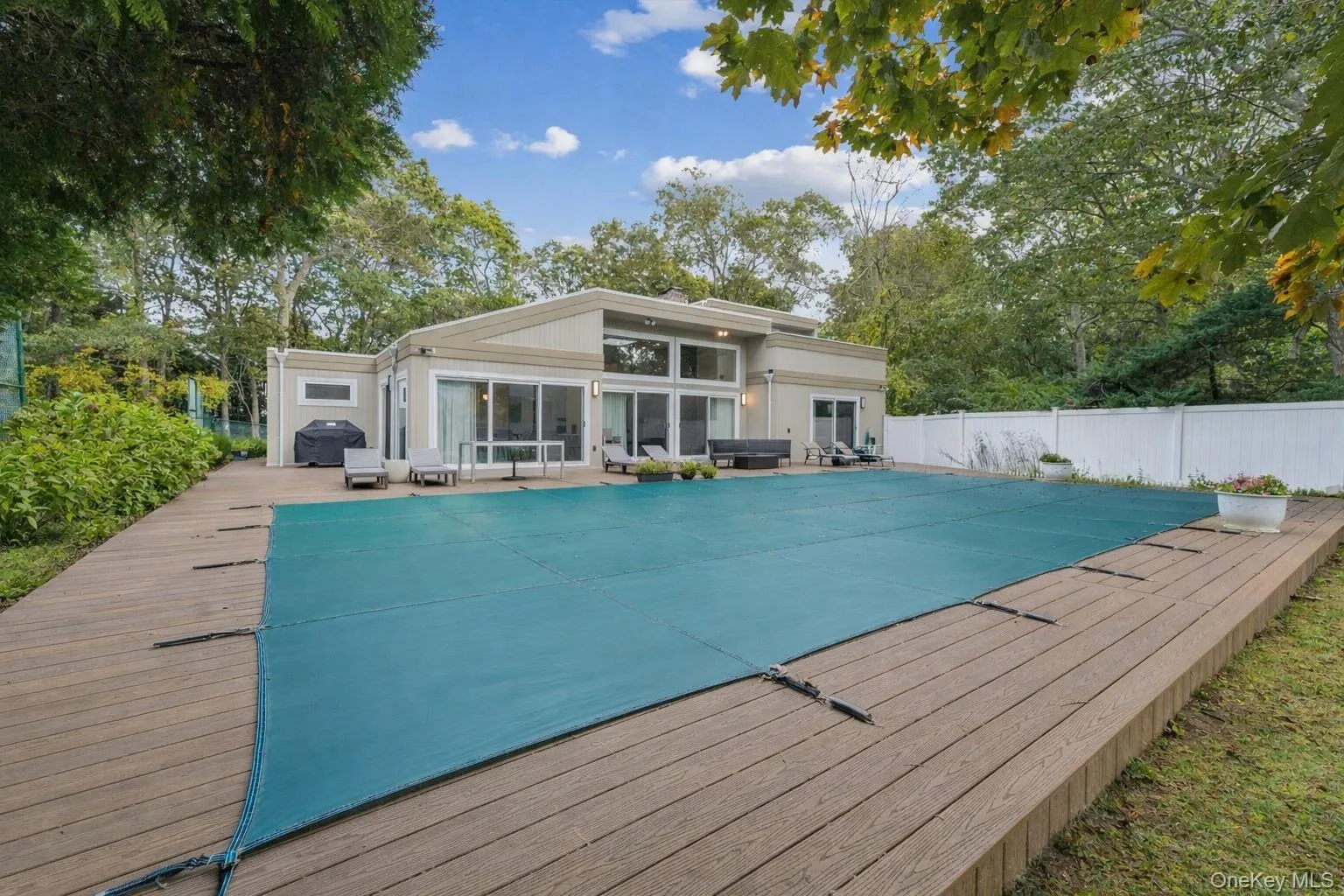 View of pool with a patio, a wooden deck, and view of scattered trees View of pool with a patio, a wooden deck, and view of scattered trees