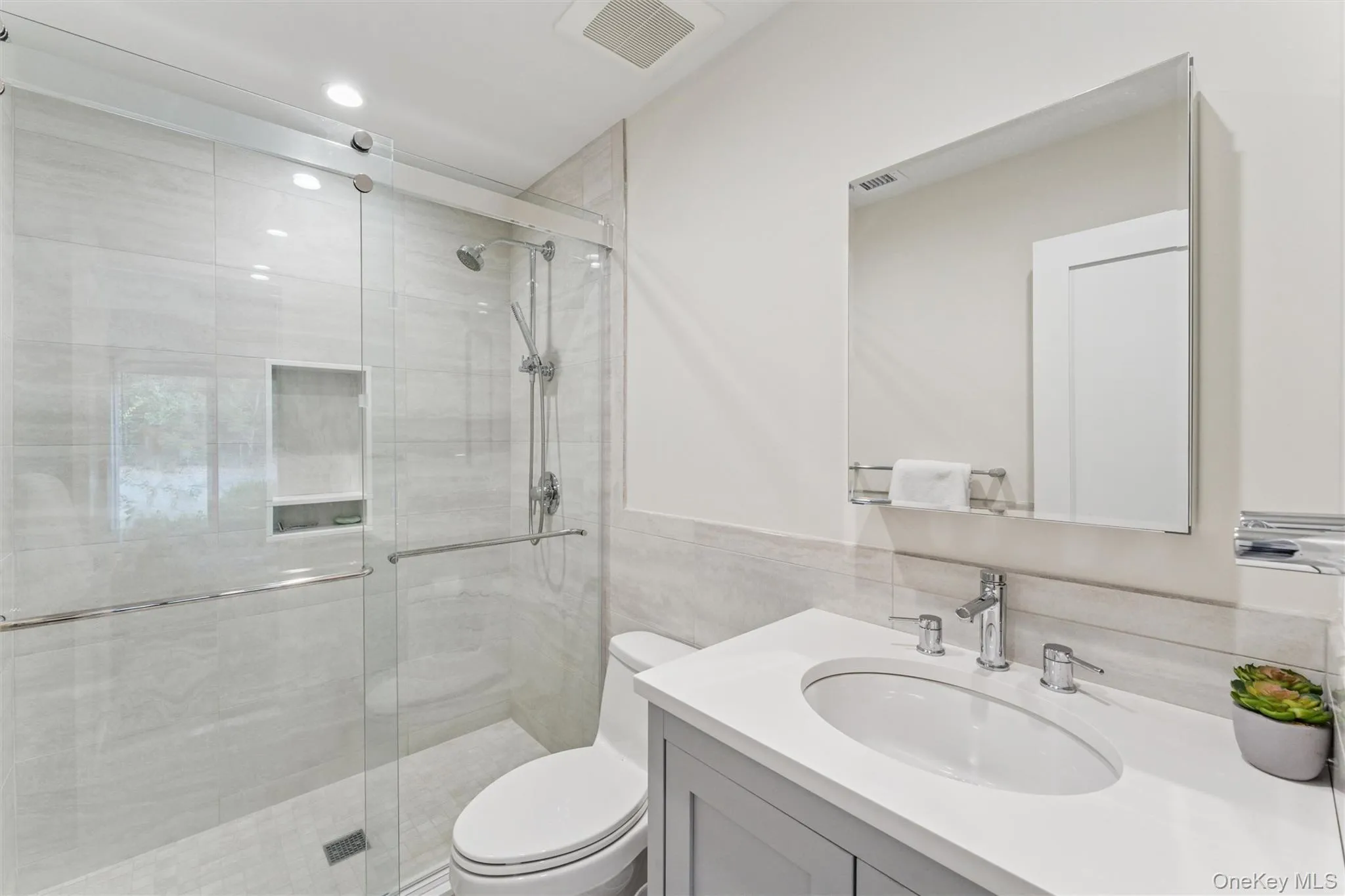 Full bath featuring vanity, a shower stall, and tile walls Full bath featuring vanity, a shower stall, and tile walls