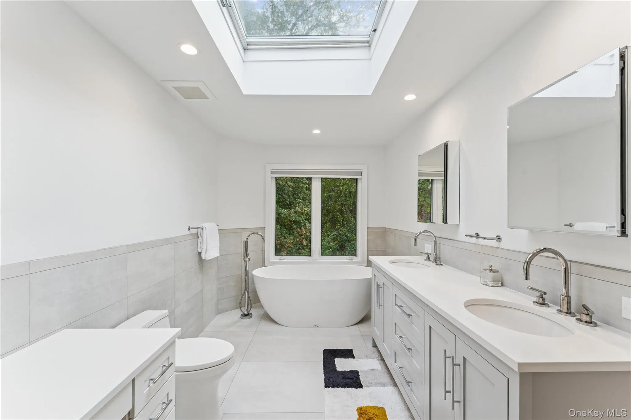 Bathroom with double vanity, tile walls, a wainscoted wall, recessed lighting, and a soaking tub Bathroom with double vanity, tile walls, a wainscoted wall, recessed lighting, and a soaking tub