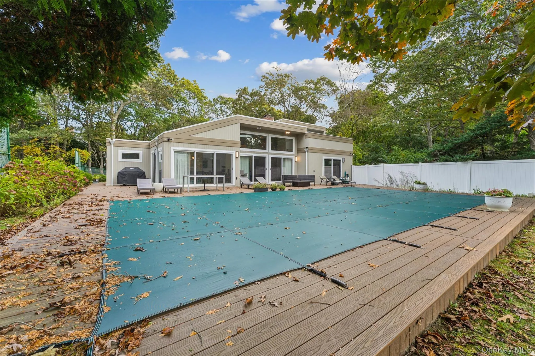 View of swimming pool with a patio area, a sunroom, view of scattered trees, and a deck View of swimming pool with a patio area, a sunroom, view of scattered trees, and a deck