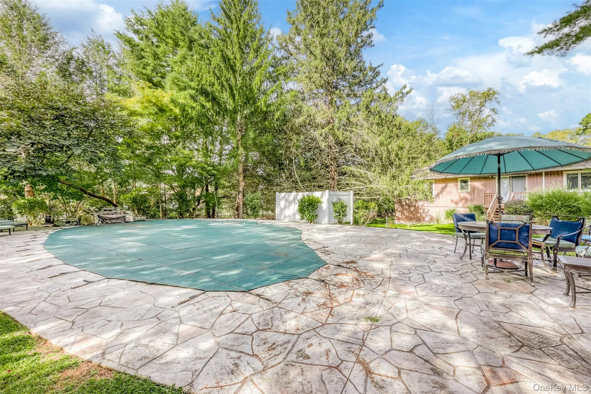 View of pool featuring a patio, view of scattered trees, and outdoor dining space View of pool featuring a patio, view of scattered trees, and outdoor dining space