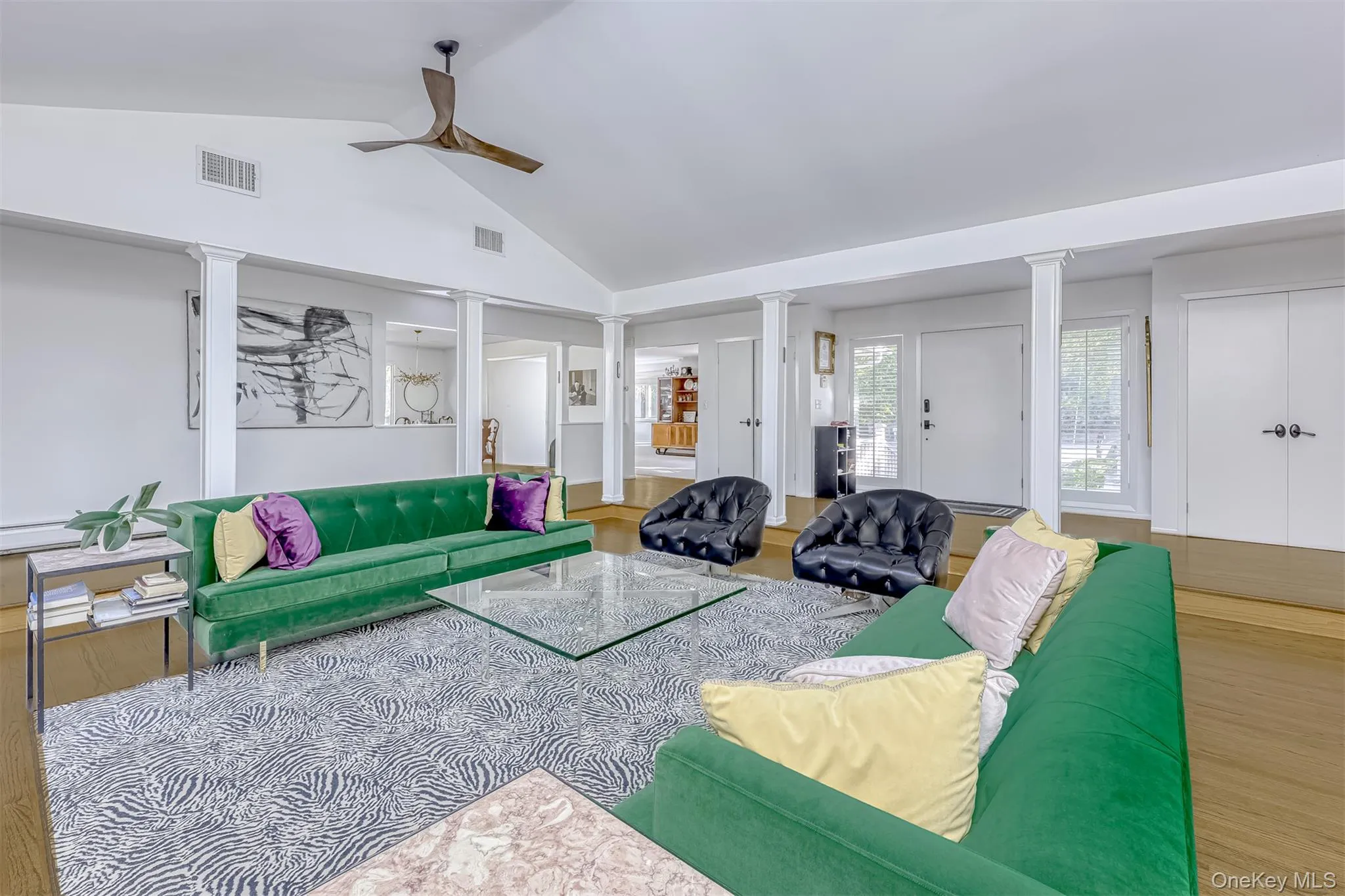 Living room with wood finished floors, a ceiling fan, decorative columns, and high vaulted ceiling Living room with wood finished floors, a ceiling fan, decorative columns, and high vaulted ceiling