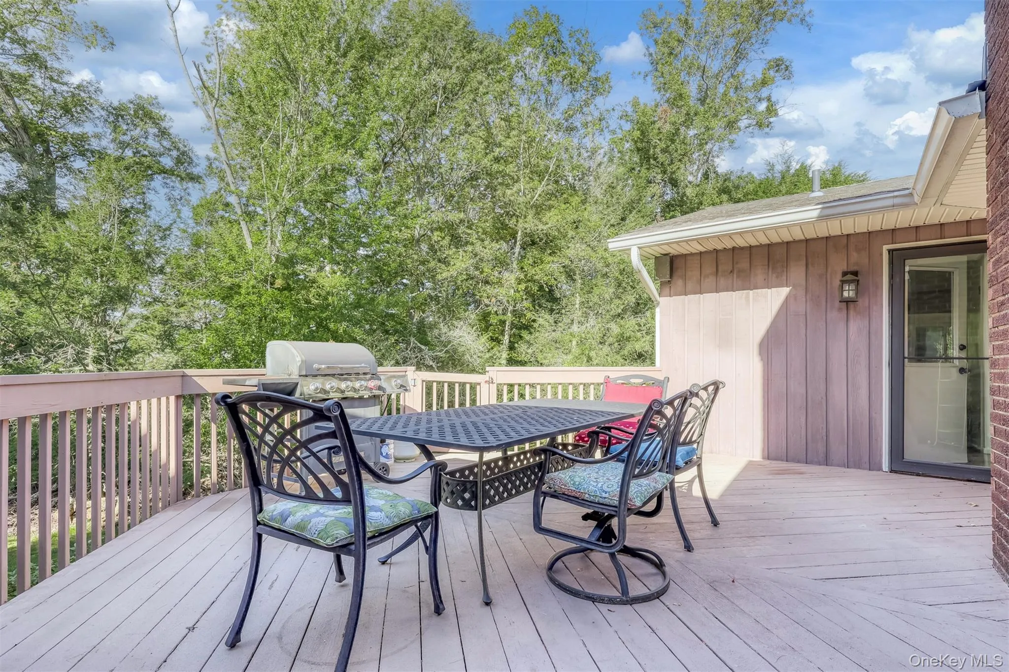 Wooden deck with outdoor dining space and view of scattered trees Wooden deck with outdoor dining space and view of scattered trees